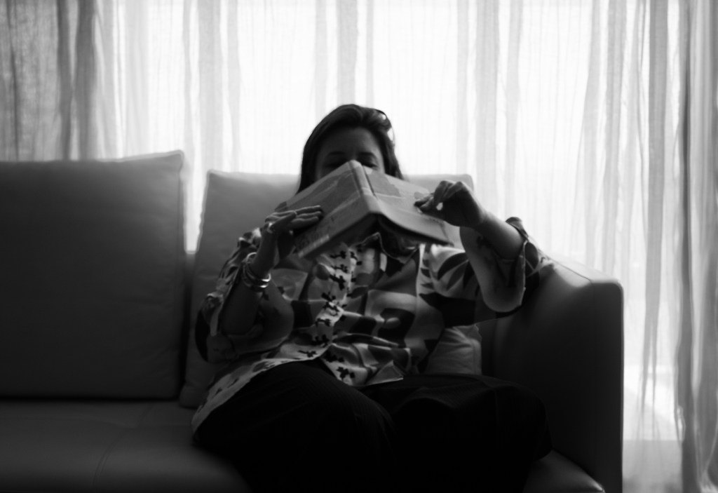 Rhéa with Murakami book on the salon couch with the curtains behind her
